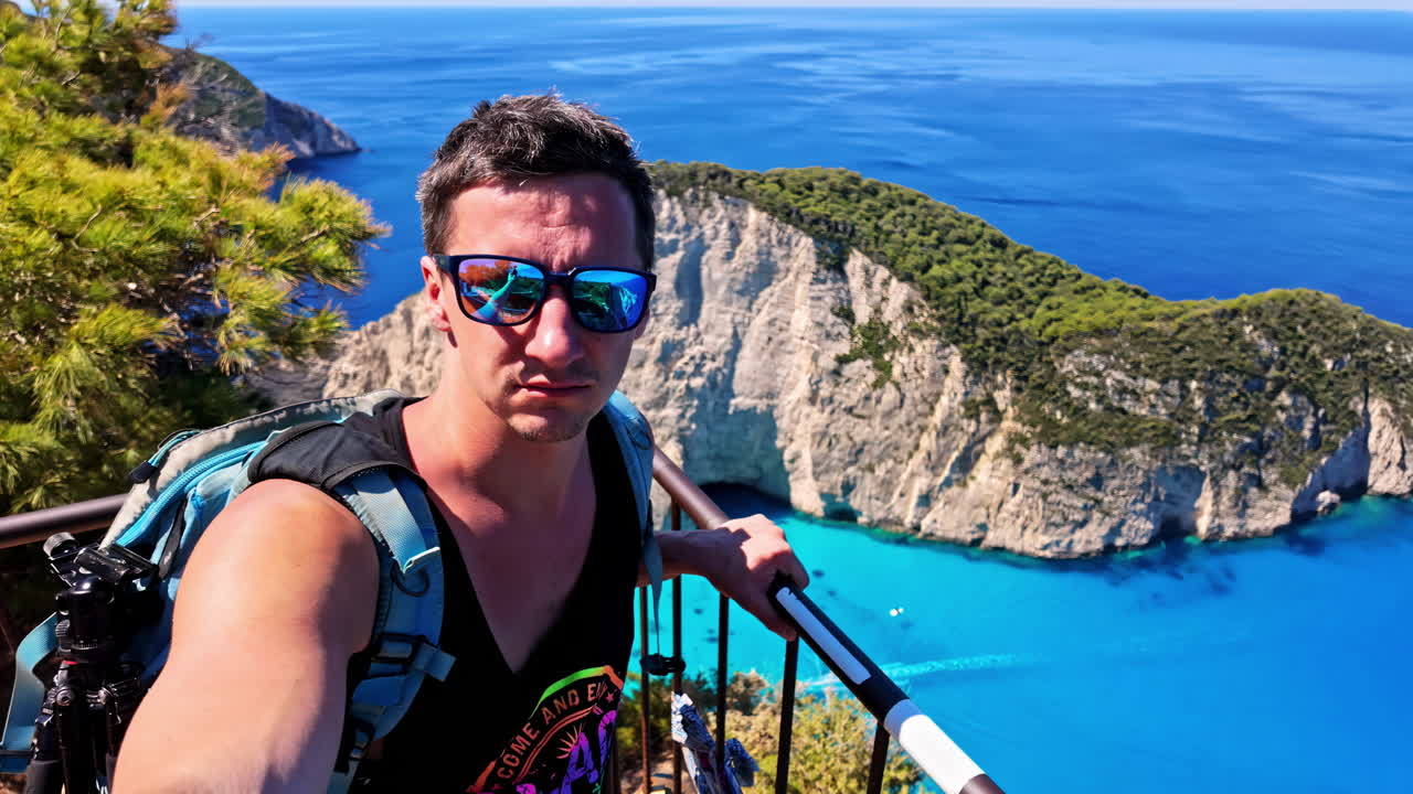 Man taking a selfie overlooking the stunning turquoise bay and cliffs of Navagio Beach, Zakynthos