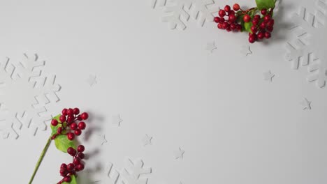 Video-of-christmas-sprigs-with-red-berries,-snowflake-patterns-and-copy-space-on-white-background