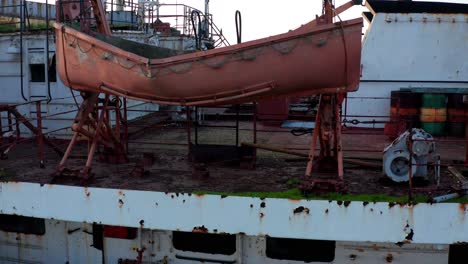 drone flies under lifeboat of abandoned rusty shipwreck