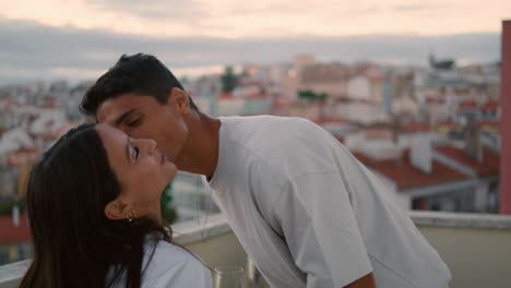 gentle spouse kissing wife sunset balcony closeup. couple having romantic dinner