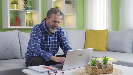 hombre maduro mirando la computadora portátil sentado en casa sintiéndose frustrado.