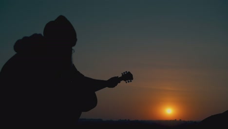 Silhouetten-Eines-Mannes,-Der-Gitarre-Spielt,-Und-Von-Menschen,-Die-Sich-Im-Lager-Ausruhen