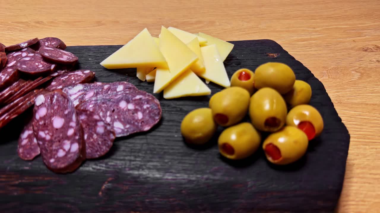 Tábua de charcutaria rústica com close-up de fatias de linguiça curada, queijos variados, picles e azeitonas