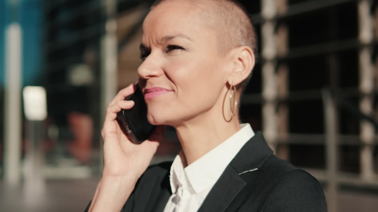 Happy Businesswoman with Shaved Head Talking on Smartphone Outdoors