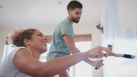 pareja decorando la habitación en la nueva casa pintando la pared juntos