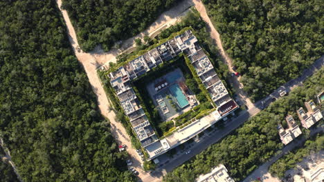 bloque de apartamentos con piscina en el patio, rodeado de árboles