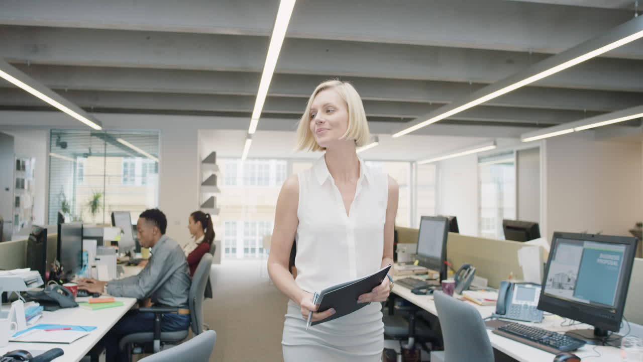 Business power woman leader walking through busy  corporate office planning her next success strategy