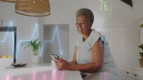 animation of cardiograph over senior african american woman using smartphone