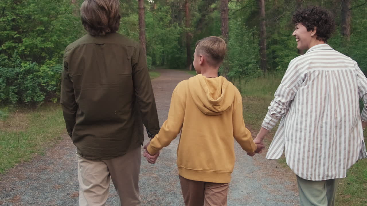 Happy Family Of Three Walking In Forest