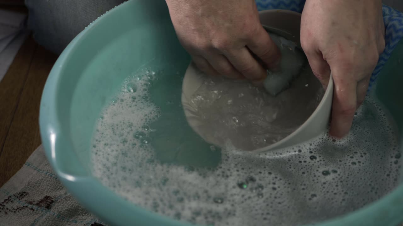 Hands washing dishes with soapy water medium shot