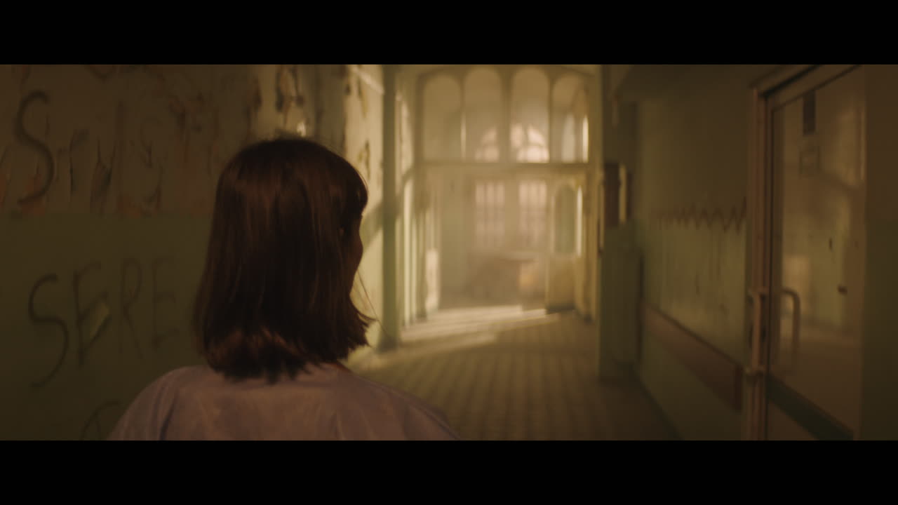 A girl and strange clown on stilts in a dark corridor at night