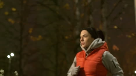 La-Cámara-Se-Enfoca-En-Una-Mujer-Con-Ropa-Deportiva-Corriendo-En-La-Ciudad-Por-La-Noche-En-Invierno