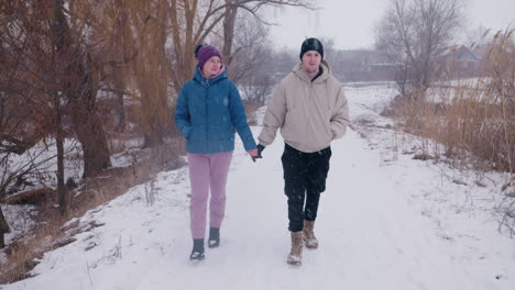 couple walking hand-in-hand in winter snow