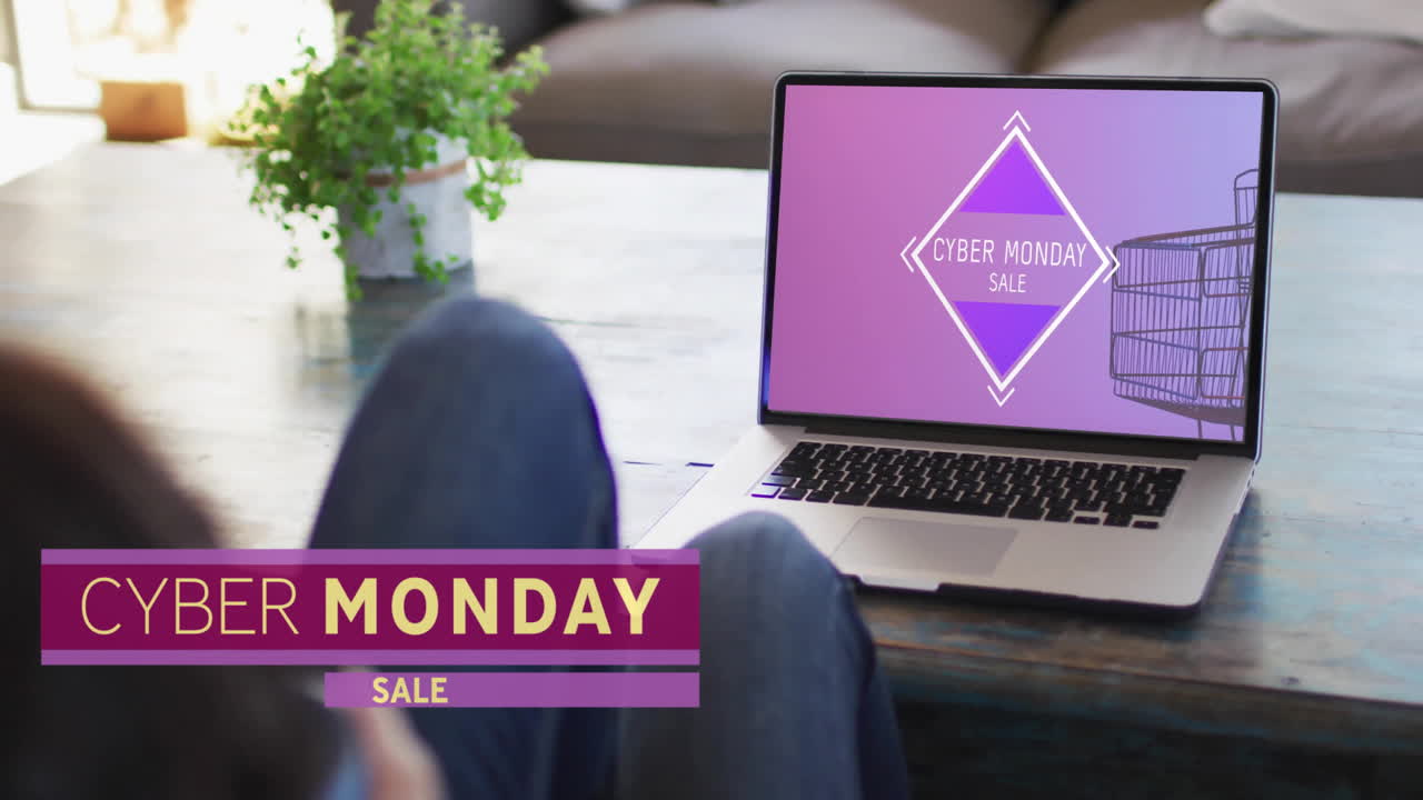 Animation of cyber monday text over woman using laptop with shopping cart on screen