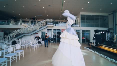 show room. woman in carnival costume in a luxury salon. people gathering in the hall before the presentation.