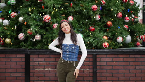 a gorgeous hispanic woman looking merry celebrating christmas with a tree and festive holiday decorations and ornaments