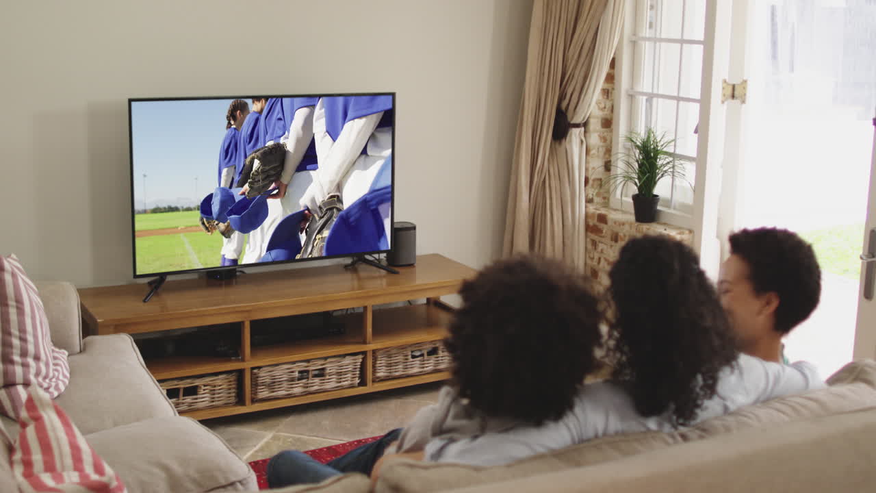 Famiglia felice seduta a casa insieme che guarda una partita di baseball in TV