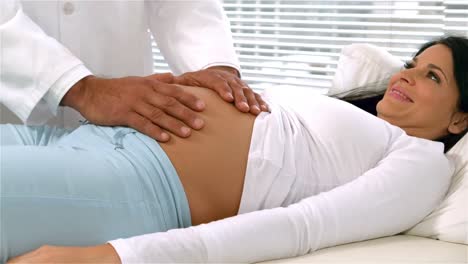 médico con las manos en el vientre de las mujeres embarazadas