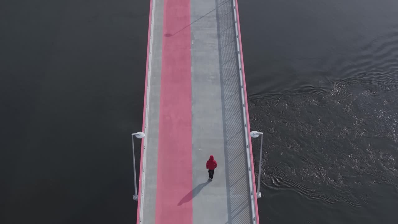 핑크색 줄무 다리의 공중 사진, 빨간색 옷을 입은 사람이 앞을 걸어가고, 느린 동작