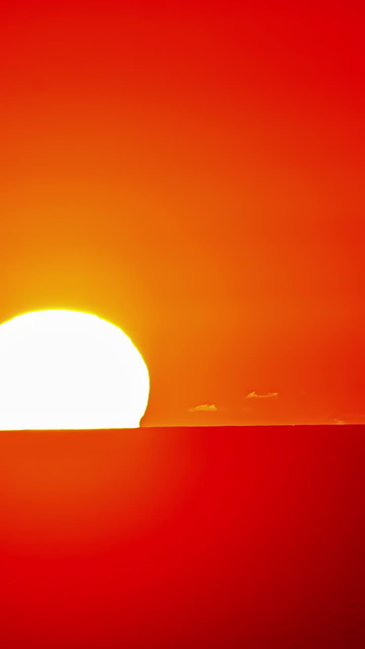 Yellow glowing sun drops below horizon as sky fades into black in wide angle timelapse view