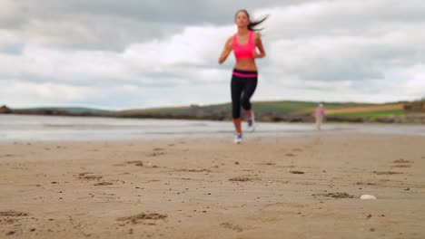 bruneta en forma corriendo en la playa