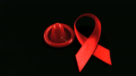 AIDS-Symbol-Mit-Roter-Schleife,-Das-Neben-Einem-Kondom-Herunterfällt