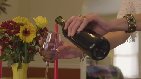 Mujer-Recogiendo-Una-Copa-De-Vino-Y-Sirviendo-Vino-Tinto-Con-Flores-Y-Velas.