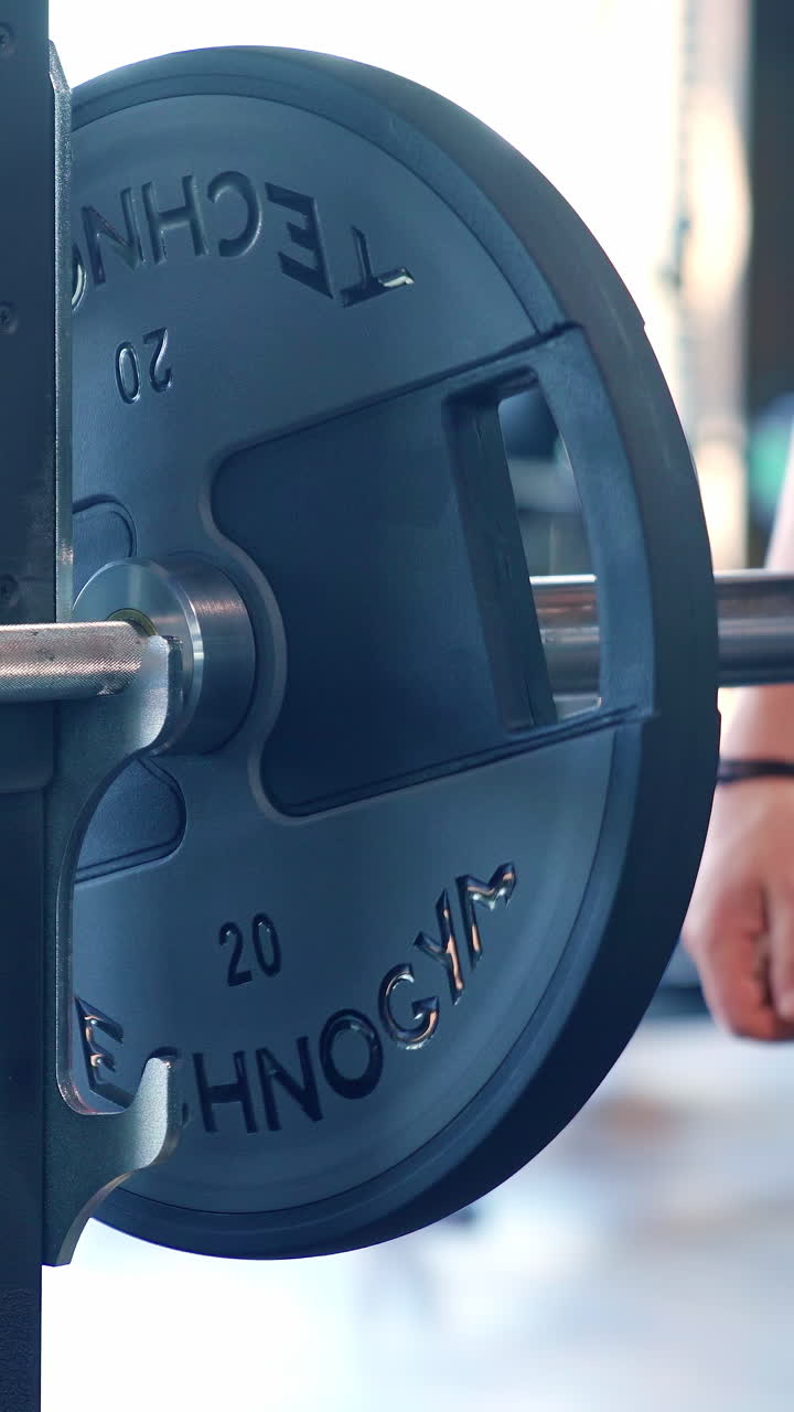 Muscular man doing training in gym. Fitness man bodybuilder training using barbell in gym. Vertical video