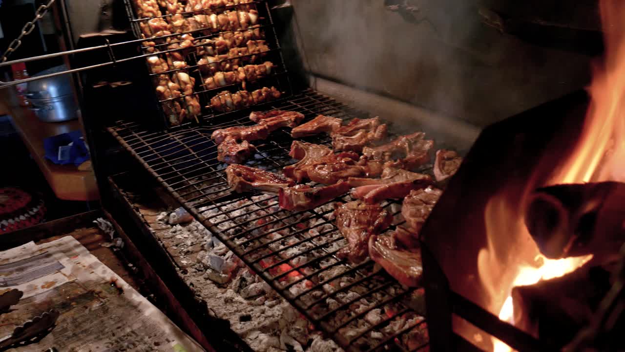 barbacoa sudafricana de chuletas de cordero y brochetas sobre un fuego de leña con brasas