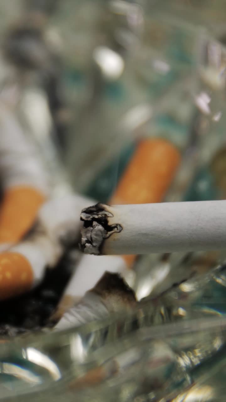 Cigarette burning down in glass ashtray, timelapse concept focusing on smoking and time passing
