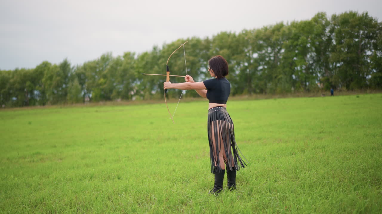 leatherclad woman in green meadow, stands alone practicing staff flow and juggling, spinning staff into smooth arcs, wearing layered leather skirt and boots, tree line on horizon, overcast sky