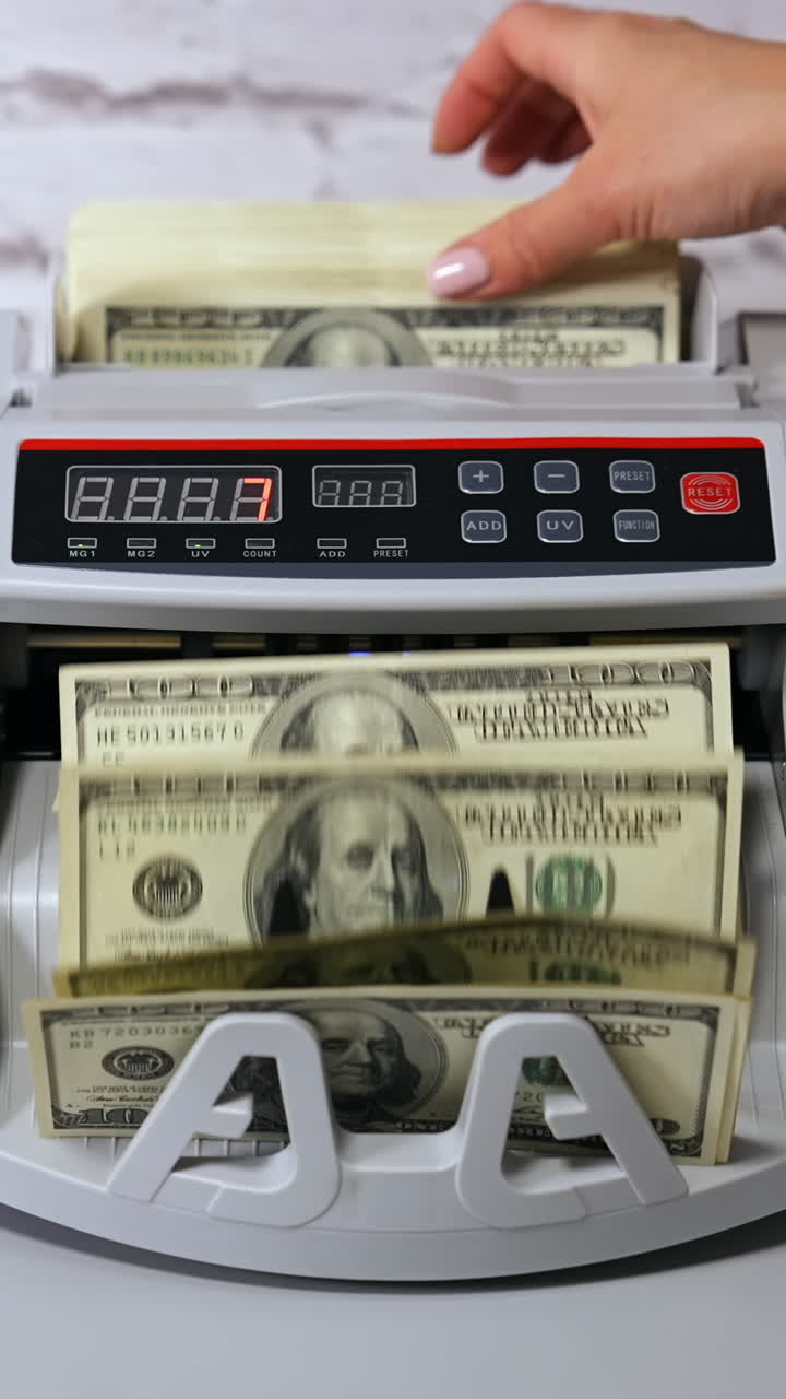 Banconote di dollari USA. Donna che inserisce denaro in una macchina contabanconote su un tavolo all'interno, primo piano. Video verticale