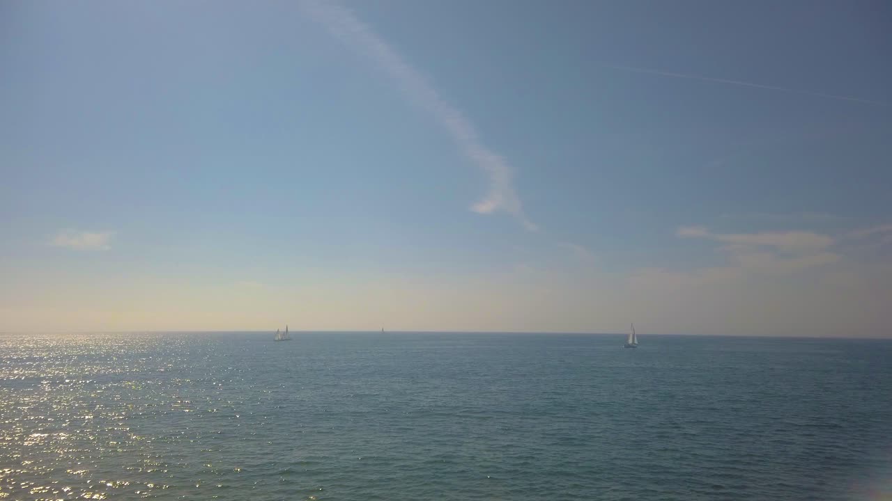 Several sailboats sailing in the beautiful ocean on a sunny day