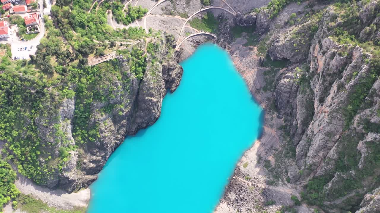Scenic winding road from Imotski to Blue lake. Aerial tilt down