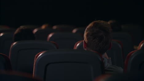 vista trasera de personas sentadas en asientos en el cine