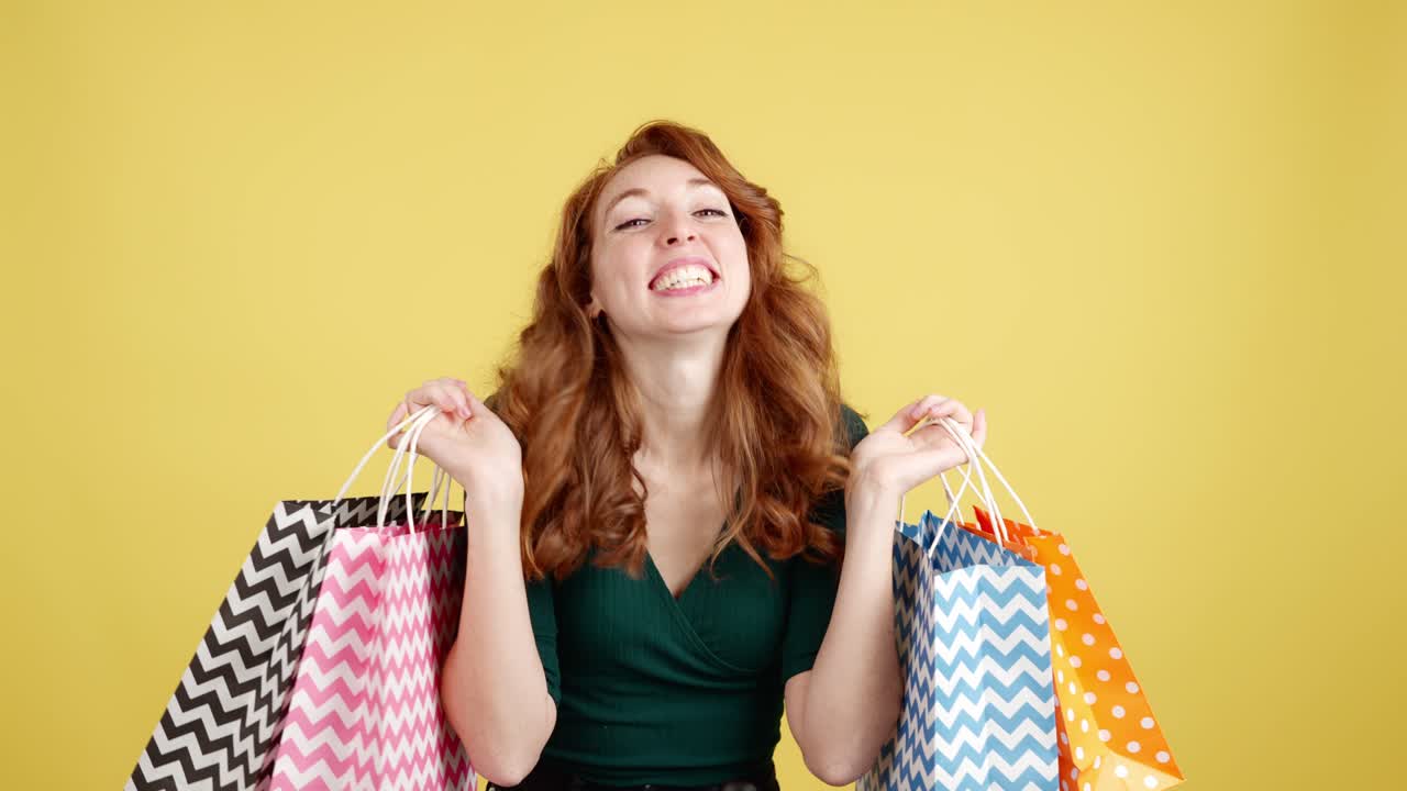 Happy Redhead Woman Showing Off Shopping Bags on Yellow Background