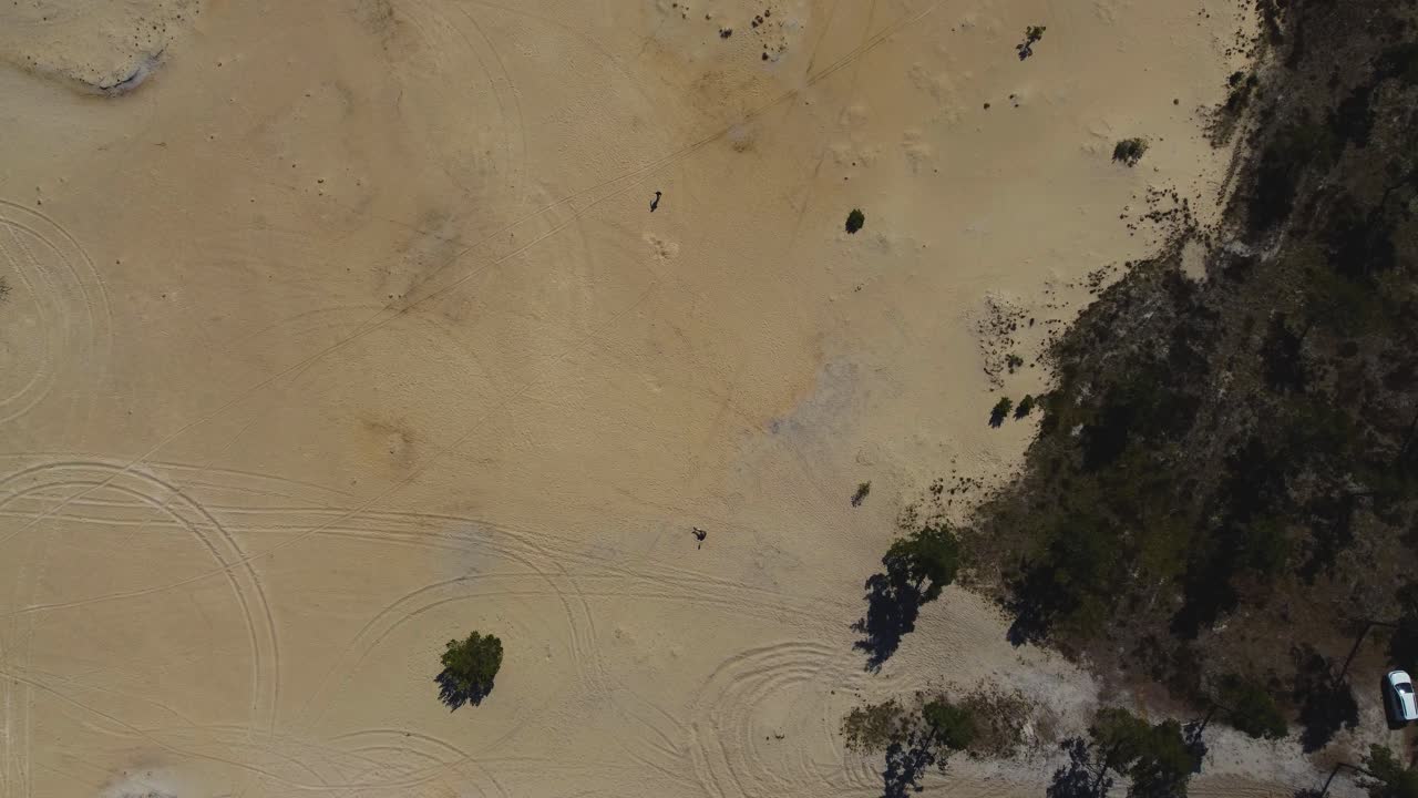 위에서: 즐거운 해변 활동 - 두 남자가 이이우마 섬에서 모래 천사를 만드는 드론 비디오 - 4k