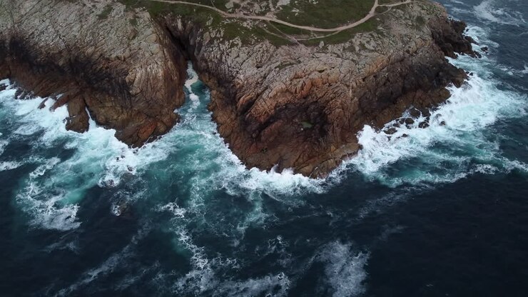 Aerial High Angle Orbit of Wild Waves Breaking on Rocky Rugged Coast