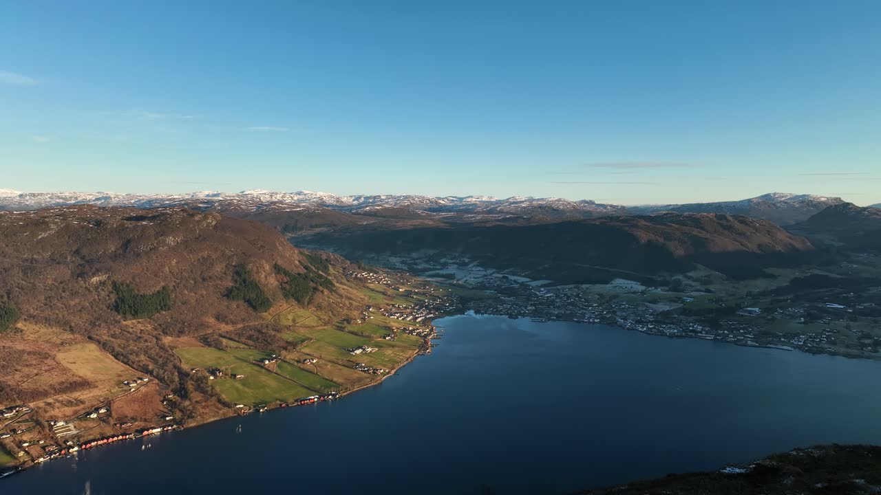 Aerial from Katanuten mountain in Vindafjord Norway. Overlooking Olensfjord, Olen village, and snowy peaks in early spring