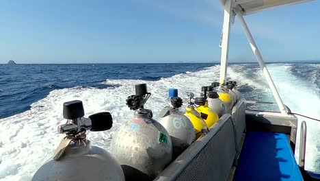 a group of sciba tanks on a boat speeding through the ocean