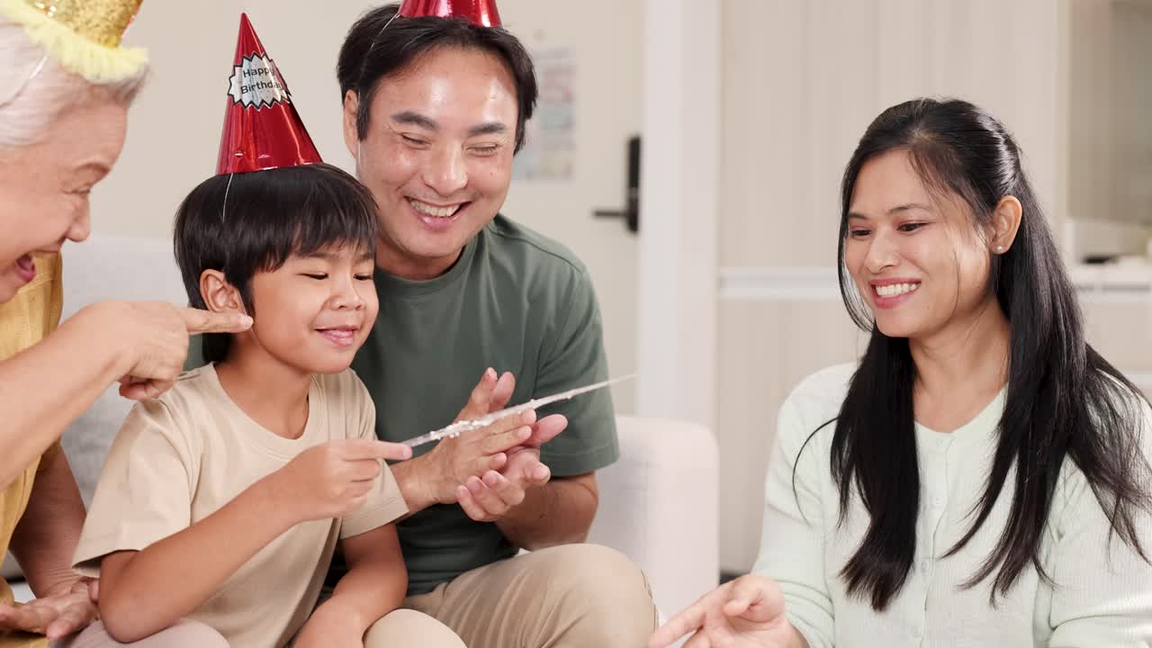 A joyful family gathers to celebrate a birthday with cake, laughter, and party hats in a cozy living room