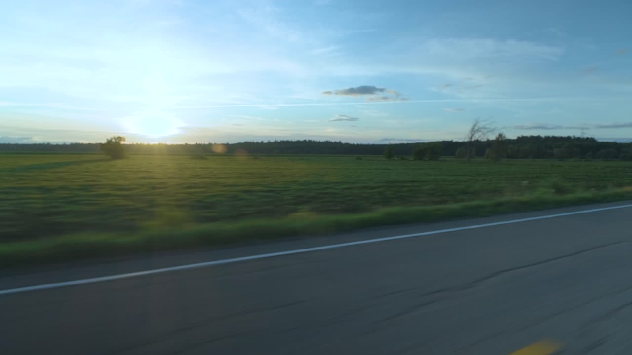 Dolly shot from a moving car on an empty rural road with beautiful rays of light in Lanaudière, Québec