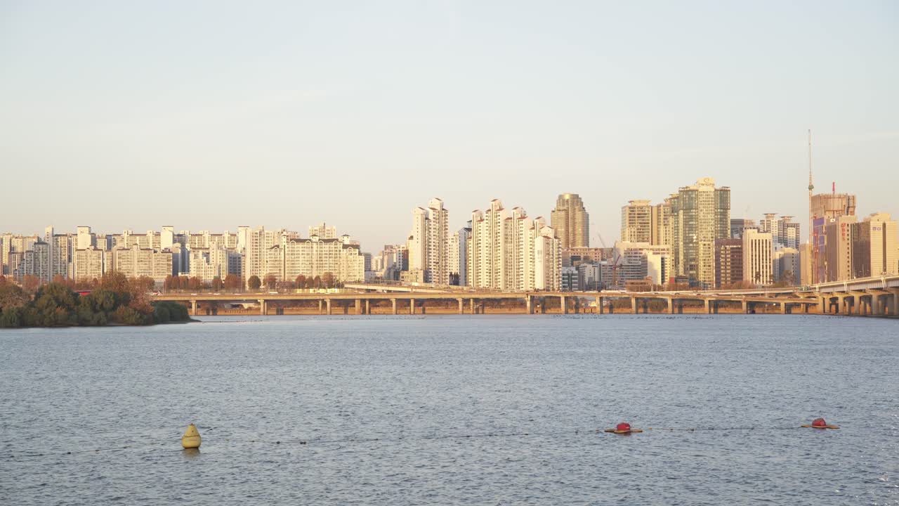 한국 서울의 한강 의 은 해가 지고, 건물들이 따뜻한 해가 지는 색으로 빛나고 있다.