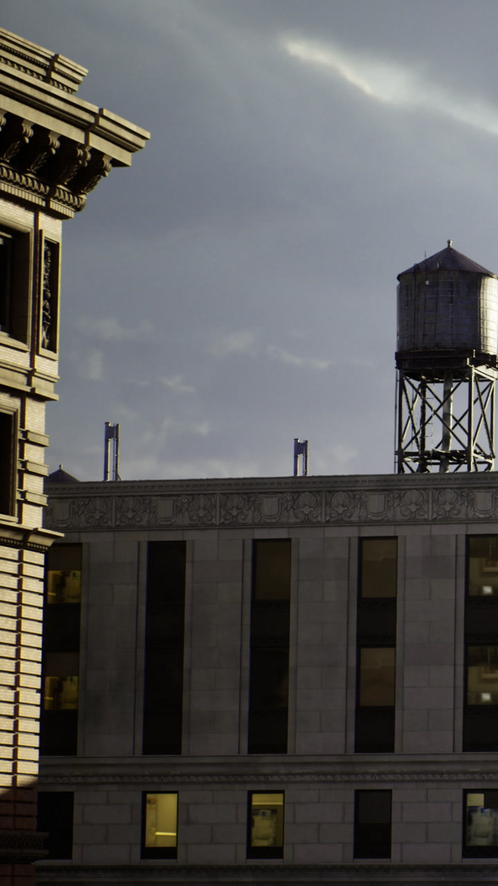 City buildings and water tower stand under a cloudy sky at sunset