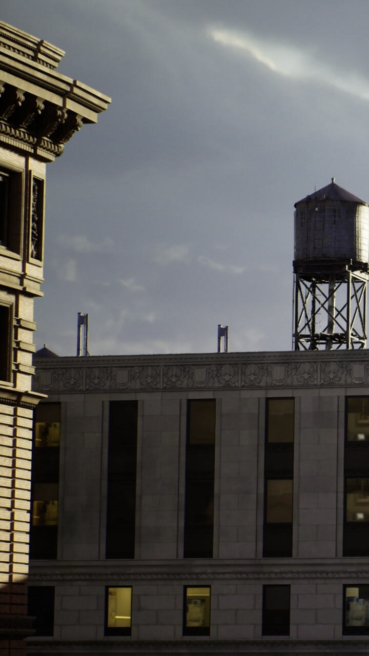 City buildings and water tower stand under a cloudy sky at sunset