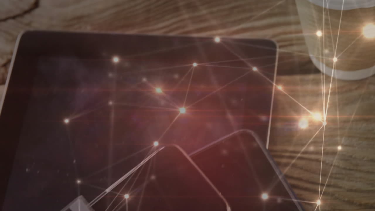 Tablet and smartphone showing digital network nodes hovering over wooden table with coffee cup