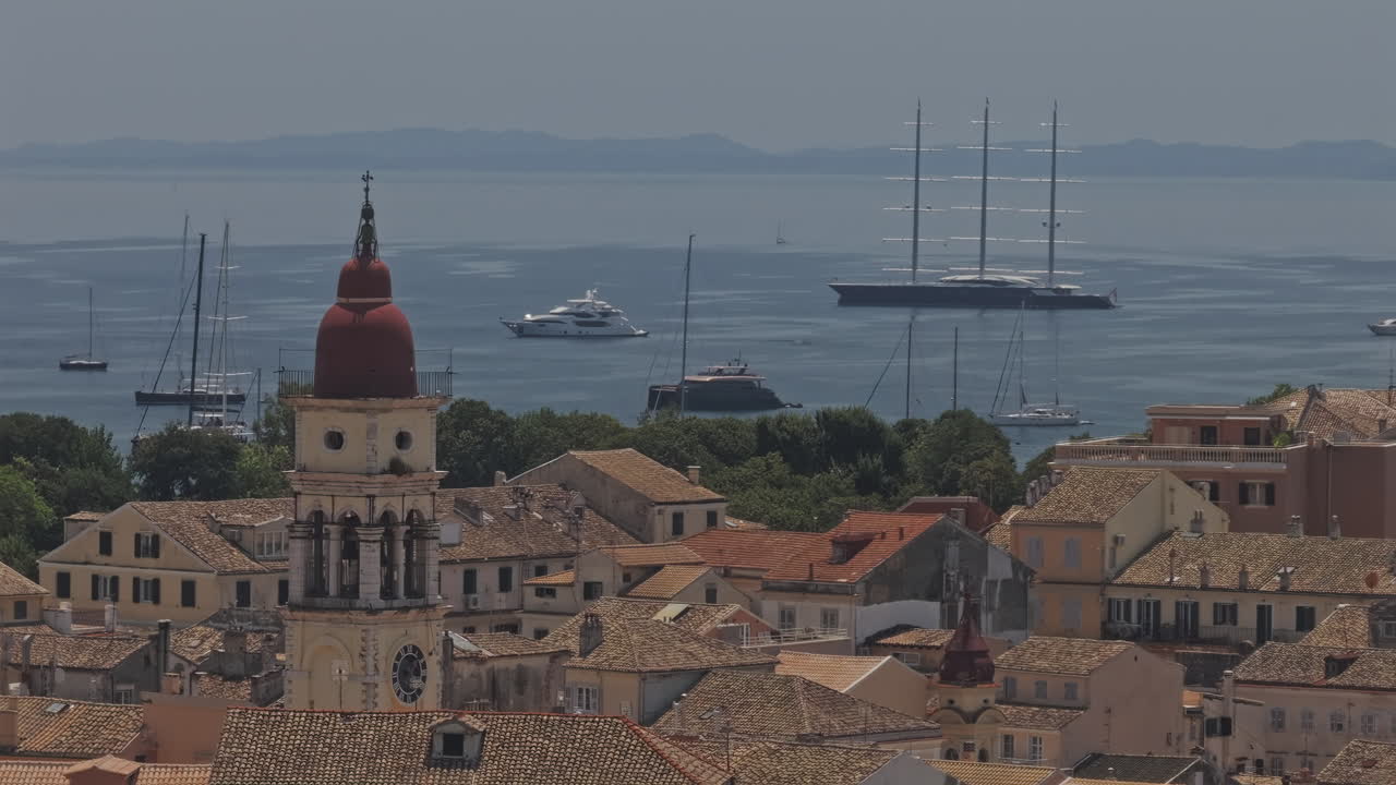 Corfu Greece Aerial v31 zoomed reverse flyover capturing the old town's rustic buildings, historic church tower, and luxury yachts in Garitsa Bay - Shot with Mavic 3 Pro Cine - July 17th 2024