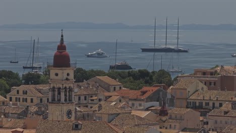 corfu greece aerial v31 zoomed reverse flyover capturing the old town's rustic buildings, historic church tower, and luxury yachts in garitsa bay - shot with mavic 3 pro cine - july 17th 2024