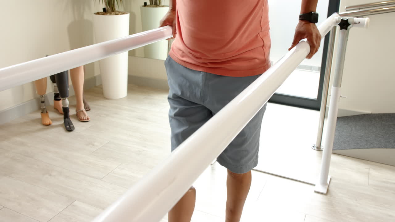 Man in prosthetic leg walking using parallel bars for rehabilitation therapy