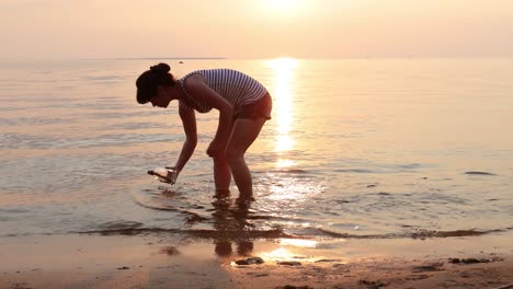 une femme a trouvé un message dans une bouteille au coucher du soleil.